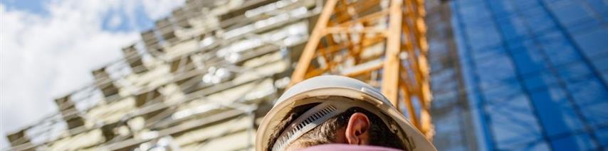 man with hard hat standing in front of scaffolding - insurance for construction professionals