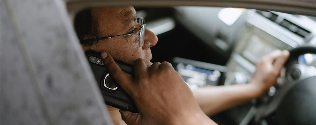 Driver using mobile phone showing the need for car insurance